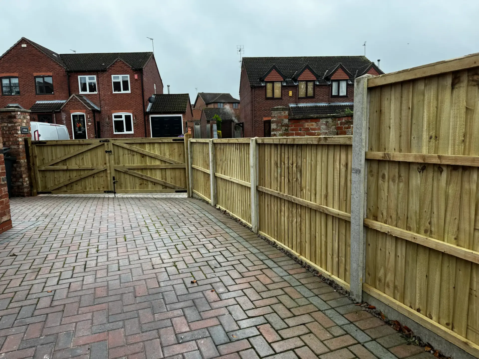 Timber fencing with concrete posts and double wooden driveway gates installed on a block-paved entrance in Gainsborough, Lincolnshire — garden boundary and gate installation by garden landscapers in gainsborough.