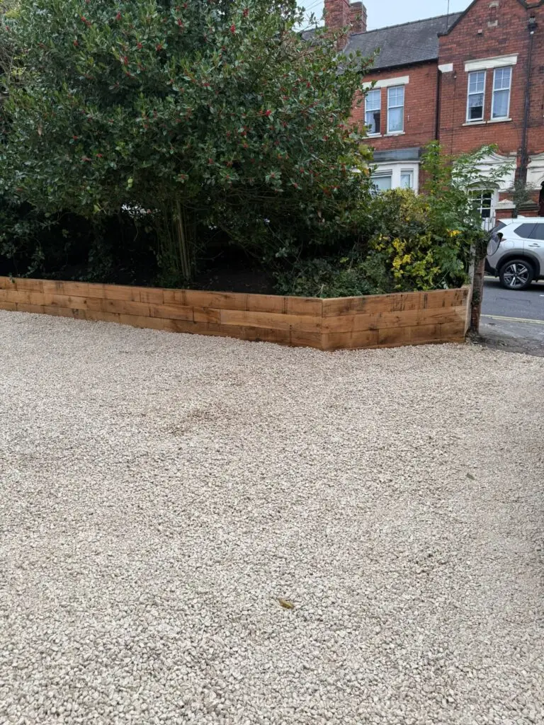 New gravel driveway installation with raised sleeper retaining wall built by landscapers in Lincoln, creating a neat, low-maintenance front garden space.