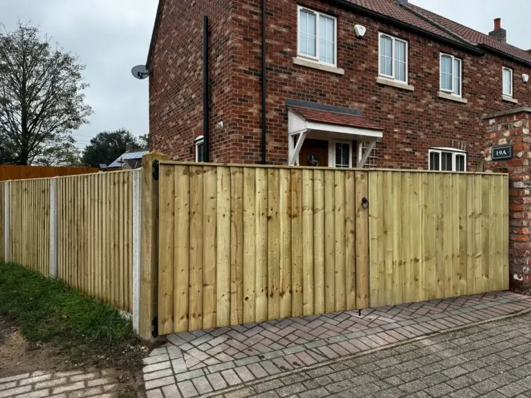 Closeboard wooden fence installation with concrete posts installed beside a red brick semi-detached house in Gainsborough, Lincolnshire, new boundary fencing by garden landscapers in Gainborough