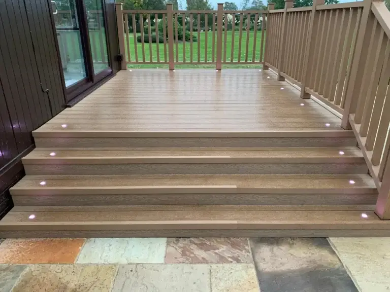 Composite decking installatio steps with integrated LED lighting installed by garden landscapers in Lincoln, joining a sandstone patio area