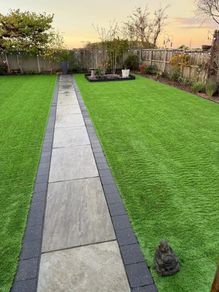 Modern garden design in Lincoln featuring a porcelain paved path bordered with charcoal edging and premium artificial grass installation by landscape gardeners.