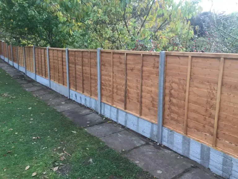 Tan-stained wooden fence panels with concrete posts and gravel boards installed along a garden pathway in Lincolnshire, durable fencing installation by garden landscapers in Lincoln
