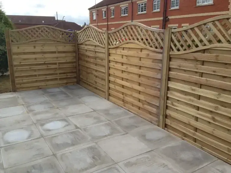 Decorative wooden fencing installation with lattice trellis tops surrounding a paved patio area in Lincolnshire, bespoke timber fence installation by garden landscapers
