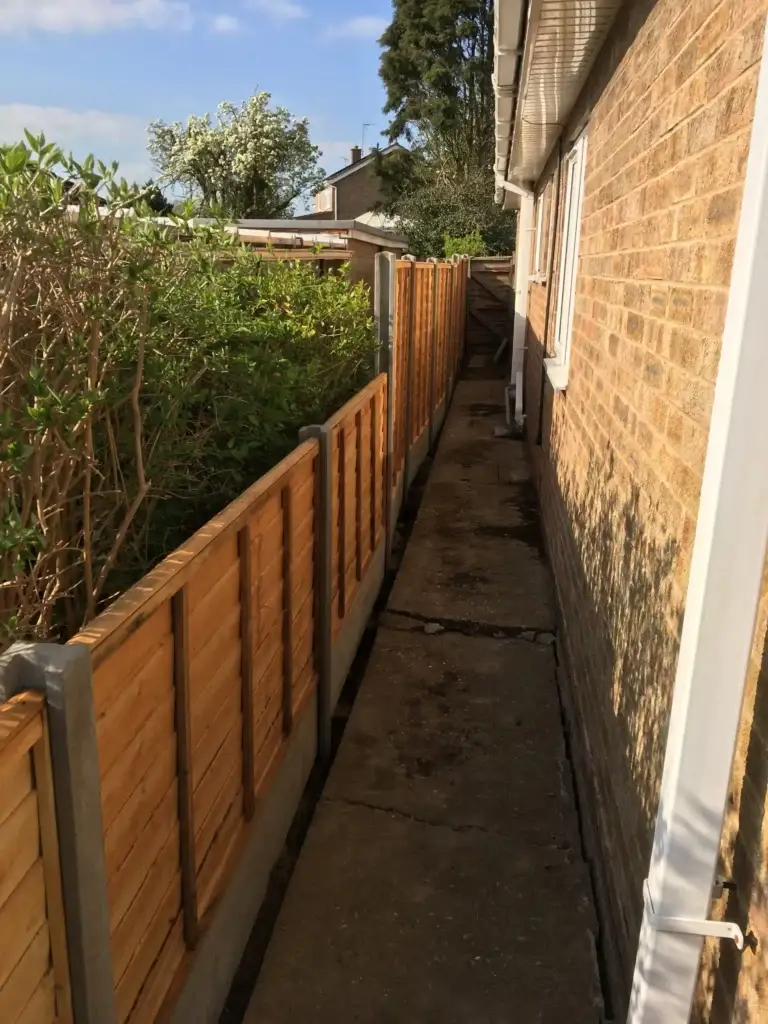 Concrete post and gravel board fencing installation with tan wood panels installed along a narrow side path beside a brick property in Saxilby, Lincolnshire, expert fencing by landscapers in Lincoln