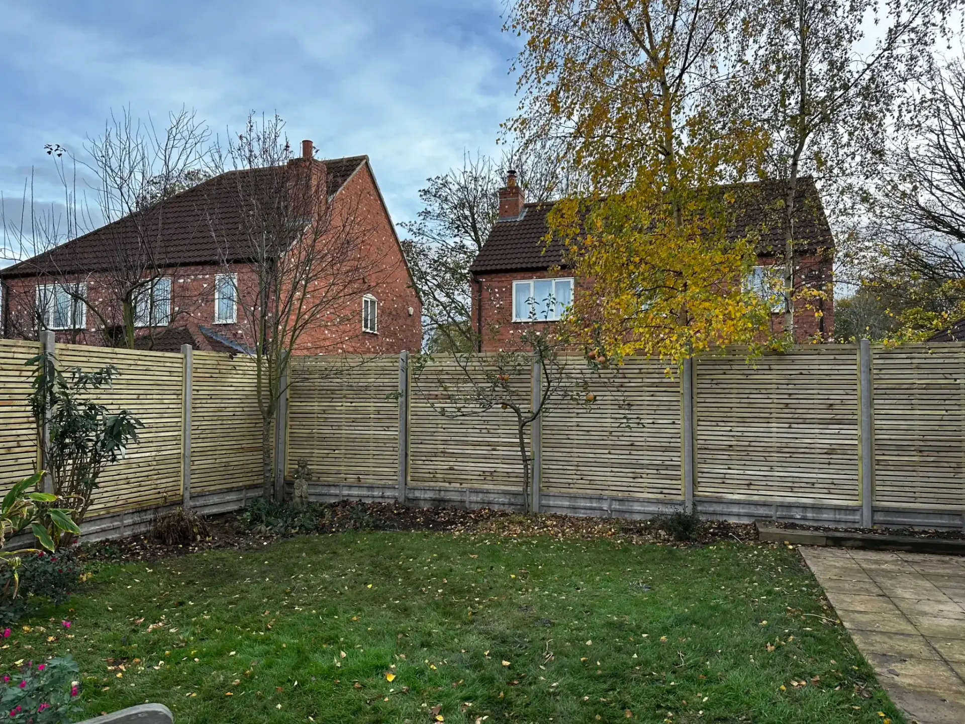 Concrete post and gravel board fencing installtion with light timber panels enclosing a landscaped garden in Lincoln, Lincolnshire — modern garden fence installation by landscapers in Lincoln