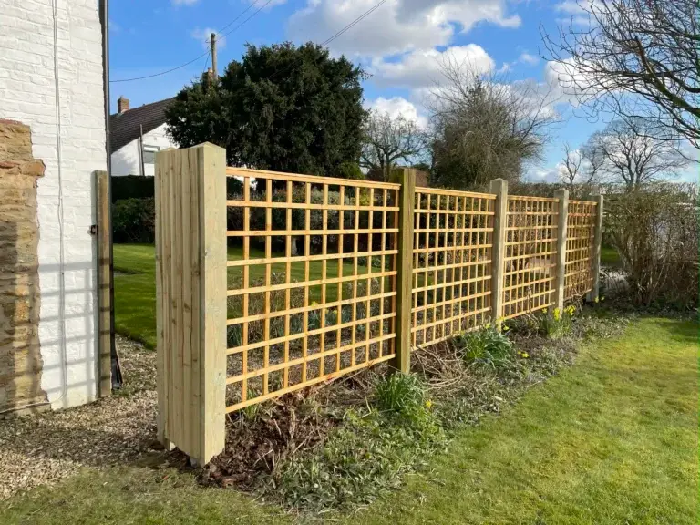 Bespoke wooden trellis fence panels installed in a landscaped garden in Saxilby, Lincolnshire, with light natural timber posts and gravel base, fencing installation by landscapers in Lincoln