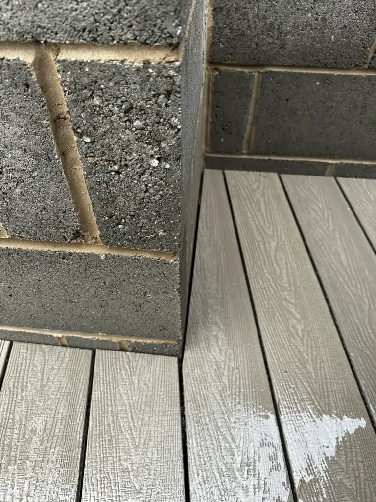 Precision-cut light grey composite decking installation by garden landscapers in Gainsborough, showing edge detail against brickwork