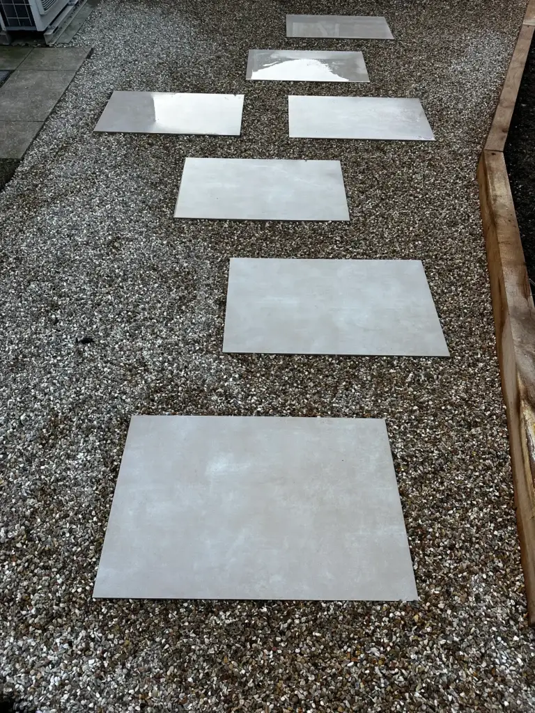 Porcelain stepping stones laid over decorative gravel, creating a clean and modern garden pathway with precise alignment and smooth texture. Installed by Lincoln based landscape gardeners.