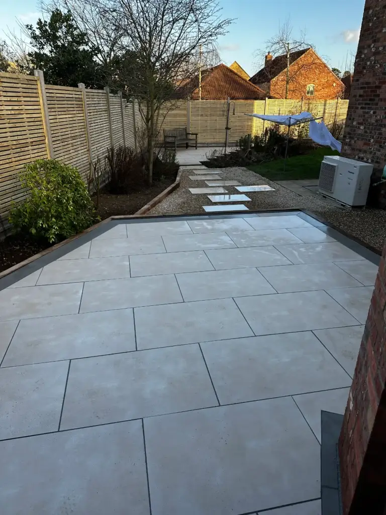 Porcelain patio and stepping stone path installation in Lincoln by landscape gardeners featuring light cream paving with charcoal edging, gravel borders, and a modern walkway leading through landscaped garden areas
