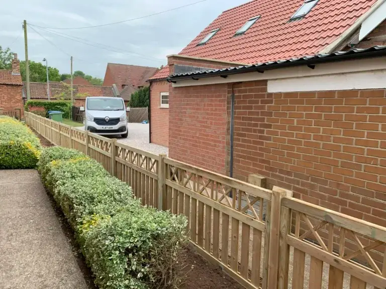 Decorative picket-style wooden fence installation with lattice top installed beside a red brick property in Saxilby, Lincoln, bespoke garden fencing by landscapers in Lincoln