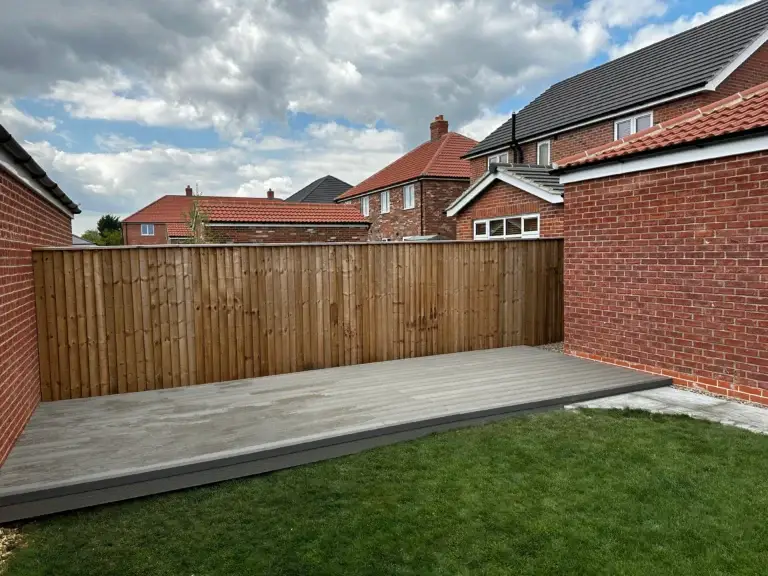 Light grey composite decking installation in Lincoln by garden landscapers, featuring clean board alignment and raised edge detail beside new turf