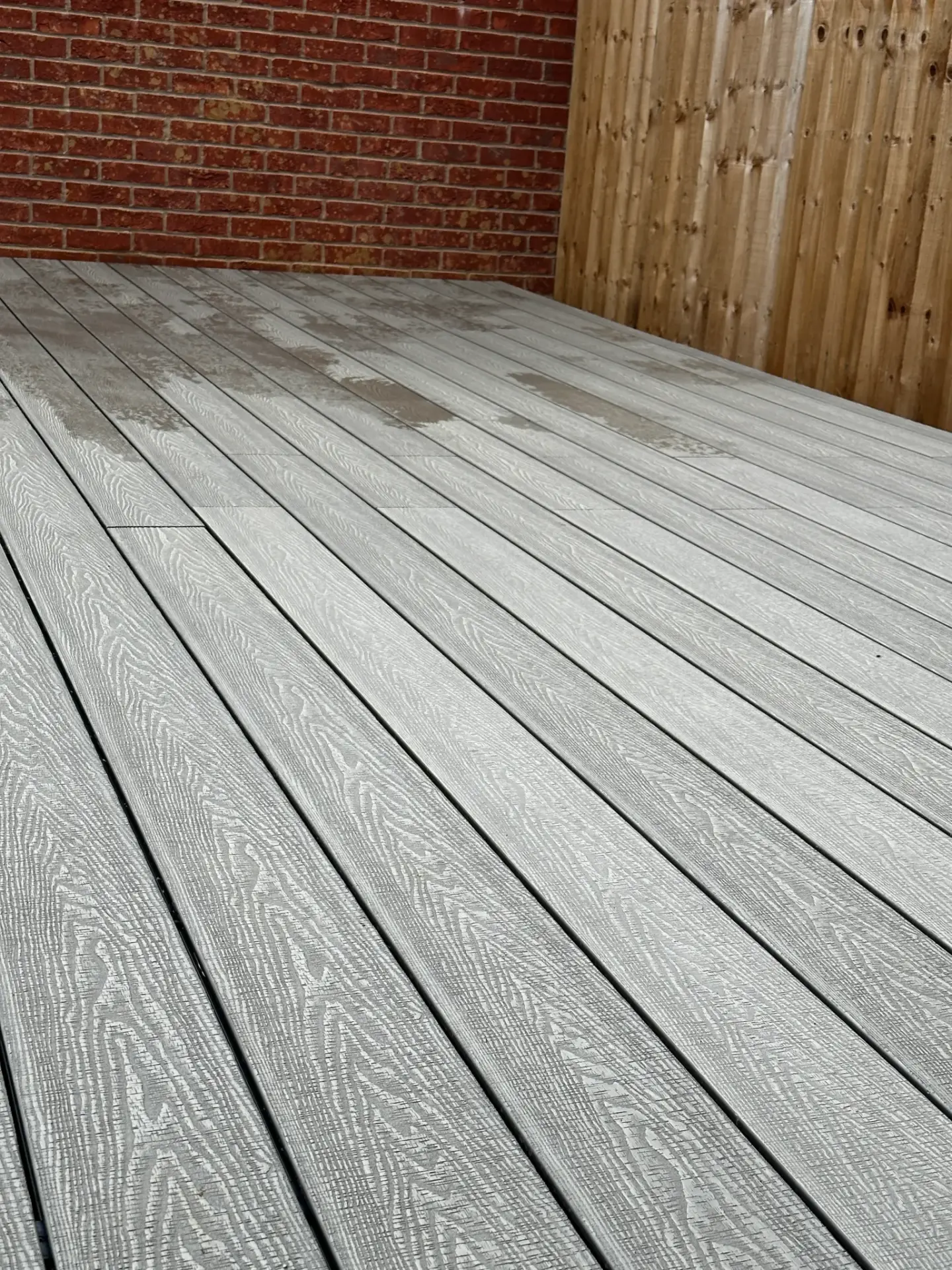 Light grey composite decking installation by garden landscapers in Lincoln, featuring realistic woodgrain texture and precision board alignment