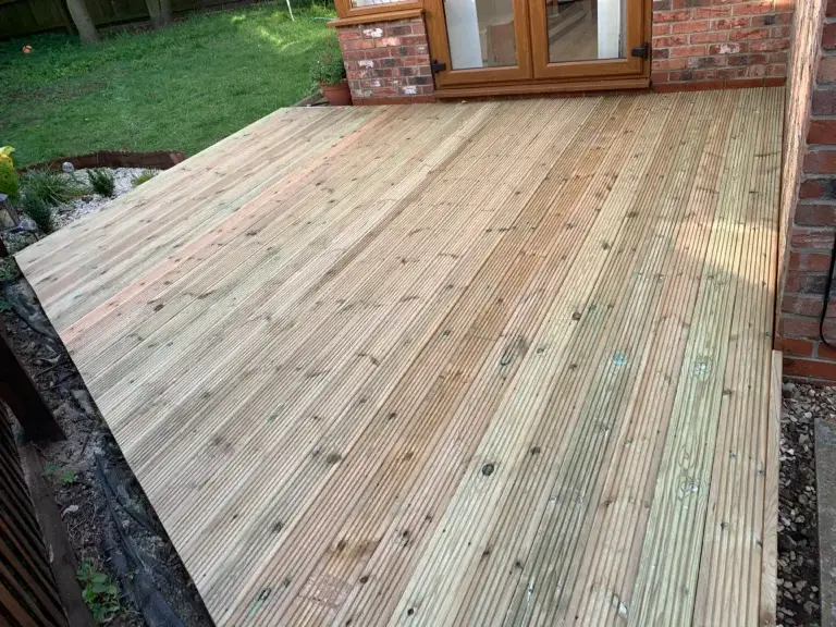 Light wooden decking installation by landscapers in Lincoln, featuring grooved anti-slip boards and a smooth transition to garden doors