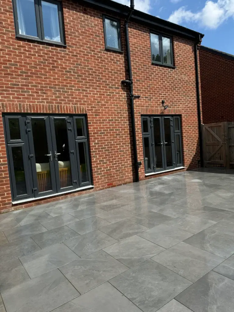 Modern grey porcelain patio installation in Gainsborough by landscape gardeners featuring large format slabs and sleek finish to complement red brick homes