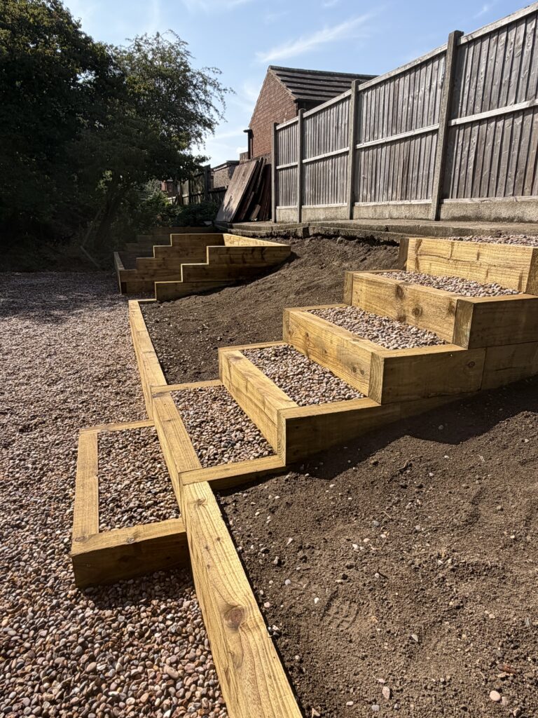 Custom-built timber sleeper garden steps and retaining walls installed in a sloping Lincoln garden as part of a full landscaping project.