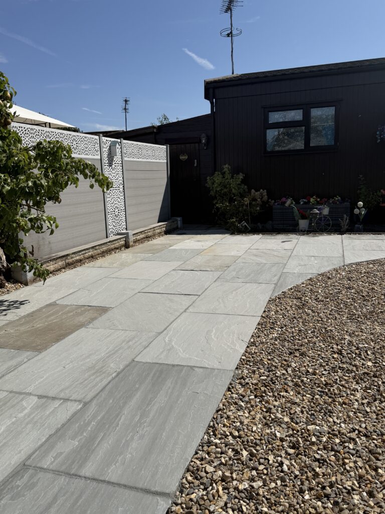 Grey riven paving path with gravel borders outside a timber lodge, laid by a landscaping company in Lincoln