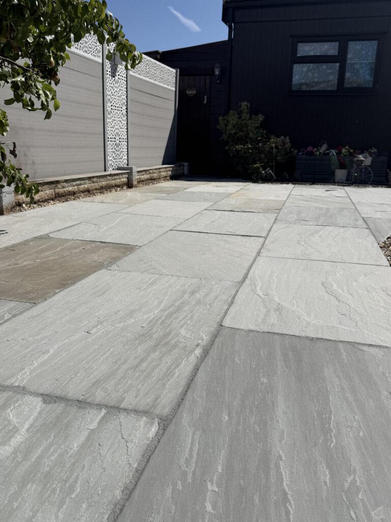 Close-up of grey riven paving slabs showing the natural surface texture on a newly laid garden patio