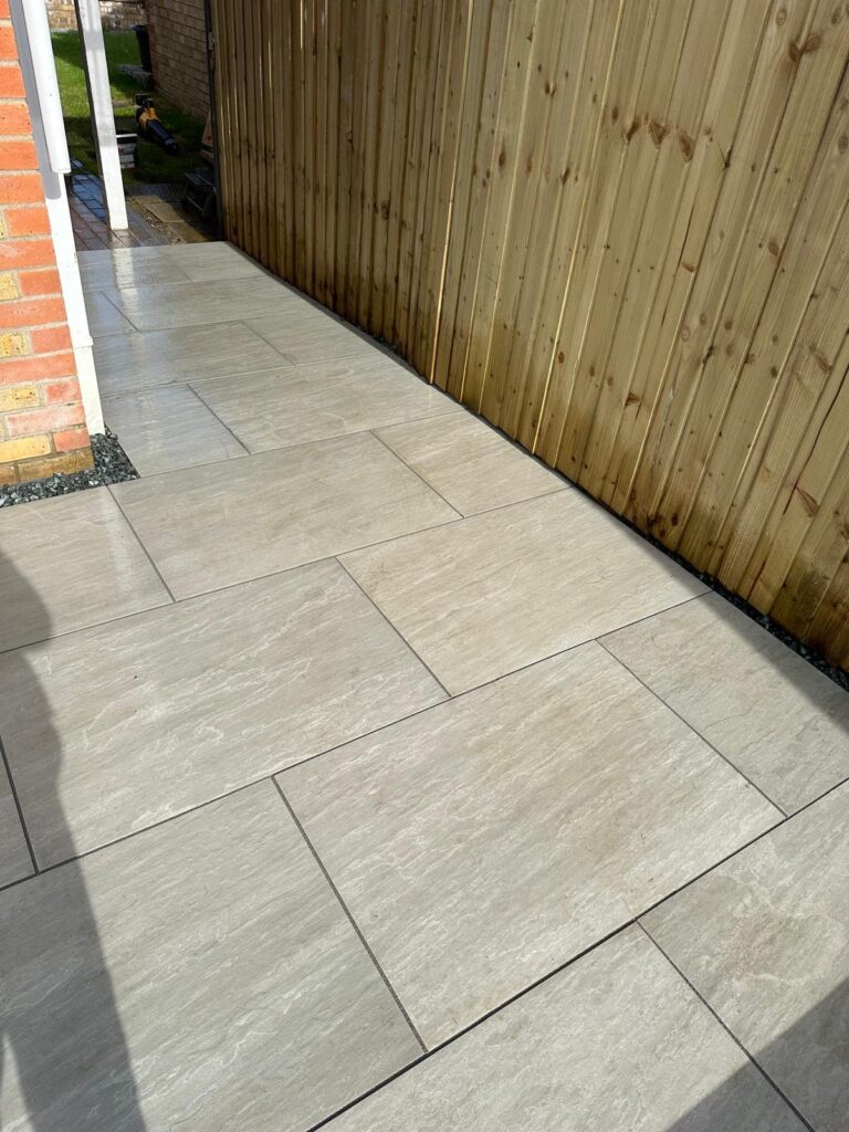 Light beige porcelain side path in Lincoln with timber fencing, dark gravel edging and a neat modern paving layout.