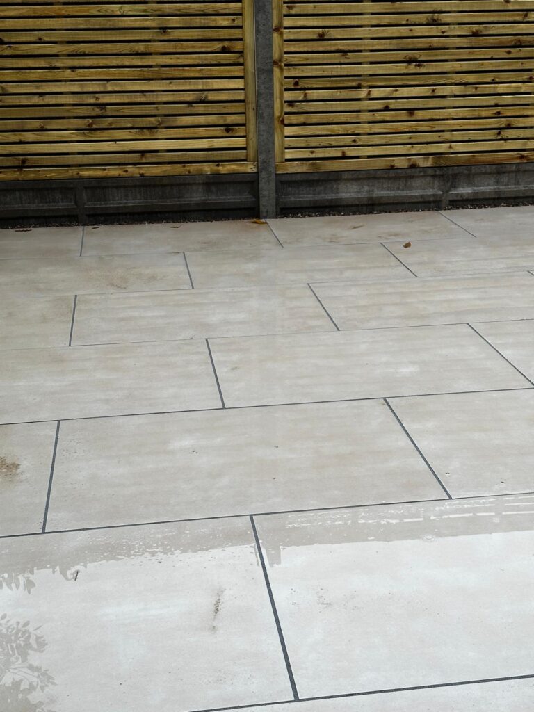 Beige porcelain patio in Lincoln with horizontal timber slatted fencing, dark grey joints and a clean modern paving layout.
