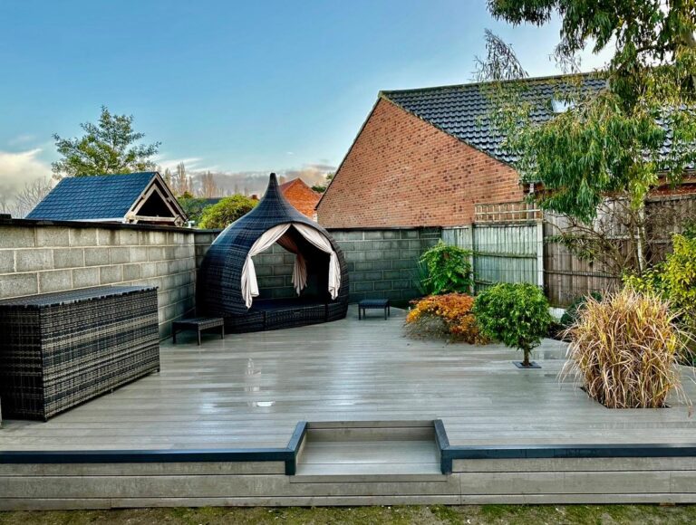 Raised composite decking in Lincoln with grey decking boards, matching step detail, black edging and contemporary planted borders