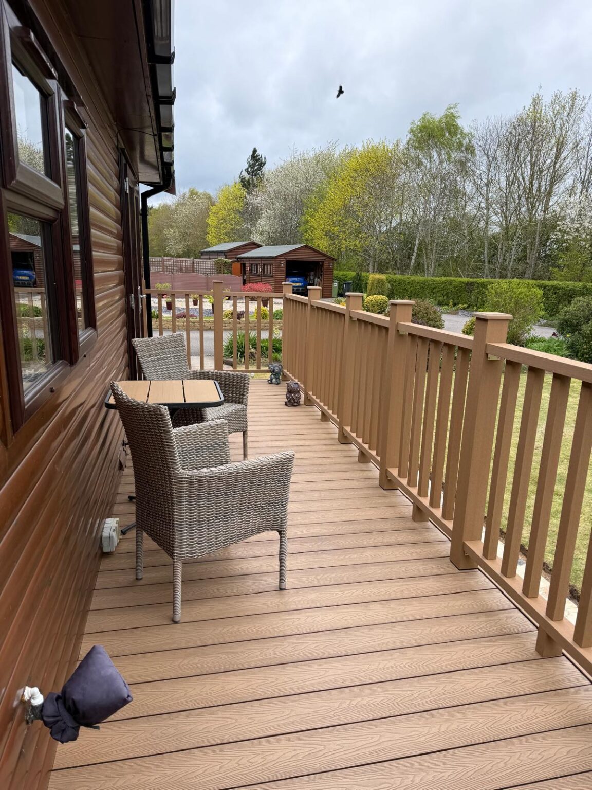 Raised light oak composite decking with tan balustrades and an outdoor seating area beside a lodge in Lincoln