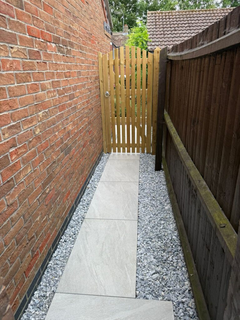 Grey porcelain side pathway with decorative gravel and timber gate installed by a landscaping company in Lincolnshire.