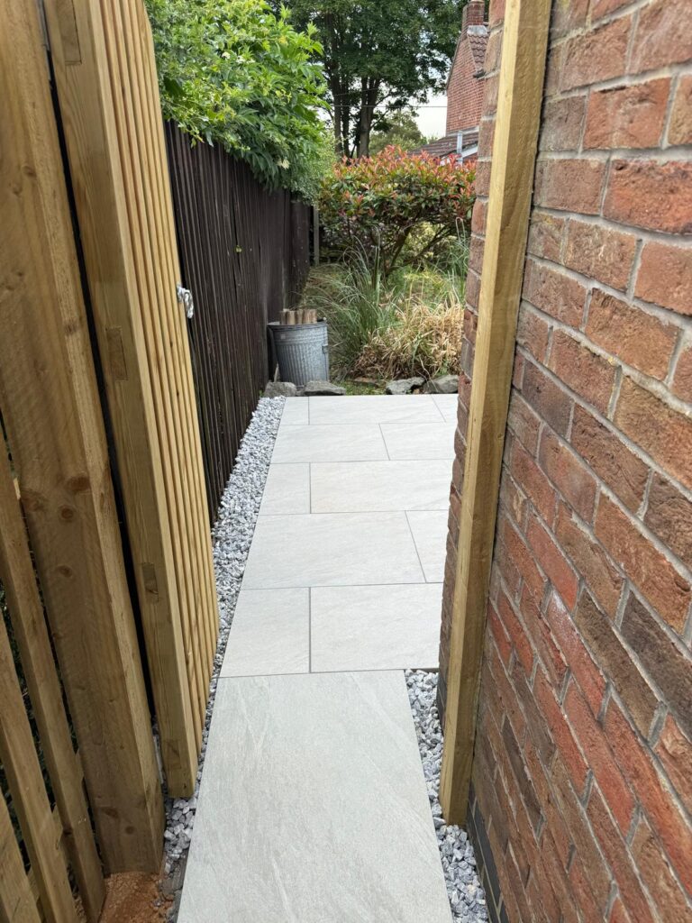 Large grey porcelain paved patio with stone-effect finish in a landscaped rear garden in Lincolnshire, laid by Reshape Landscaping