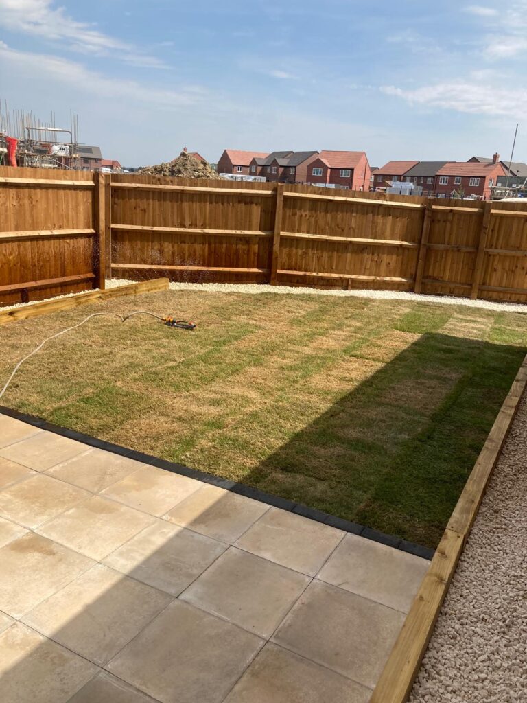 New build garden landscaping in Lincoln, UK with Indian sandstone patio, timber edging, decorative gravel borders, fresh turf lawn and timber fence installation.