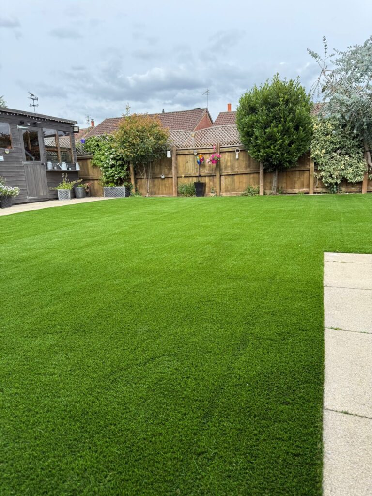 Realistic artificial grass with a natural-looking pile in a Lincoln garden framed by mature trees
