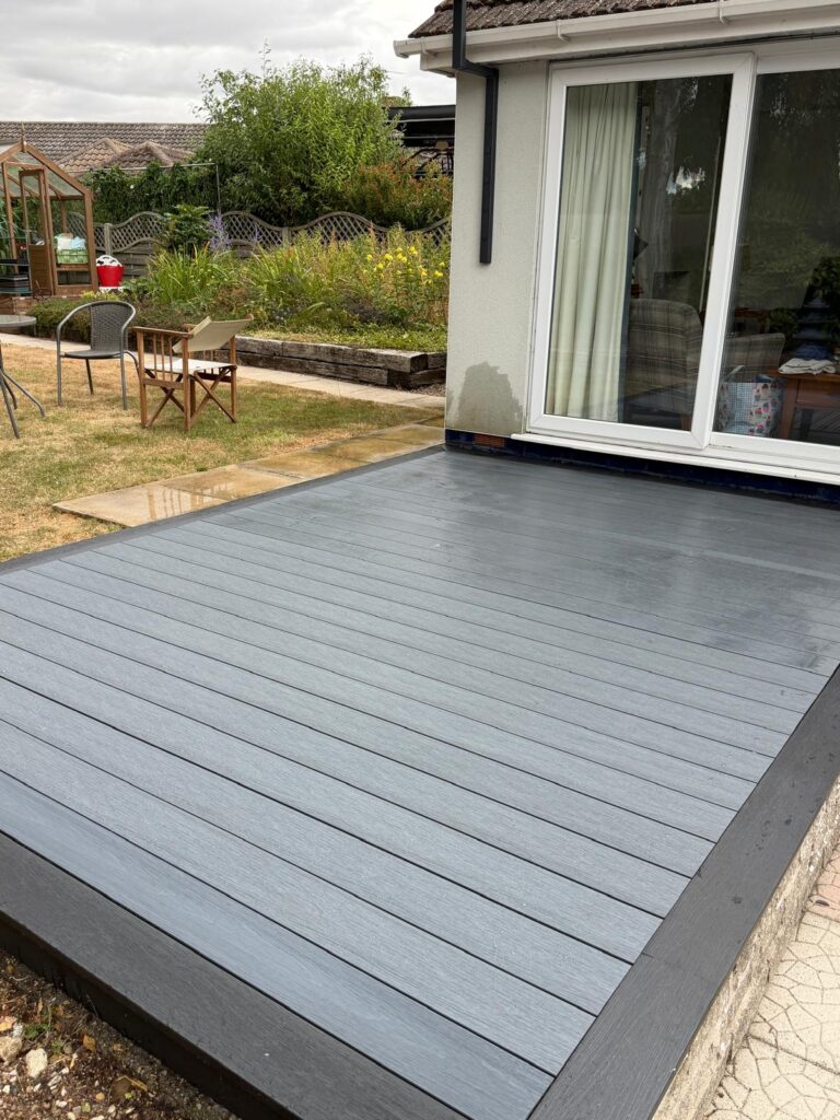 Grey woodgrain composite decking with charcoal border outside bungalow patio doors by Lincoln composite decking installers