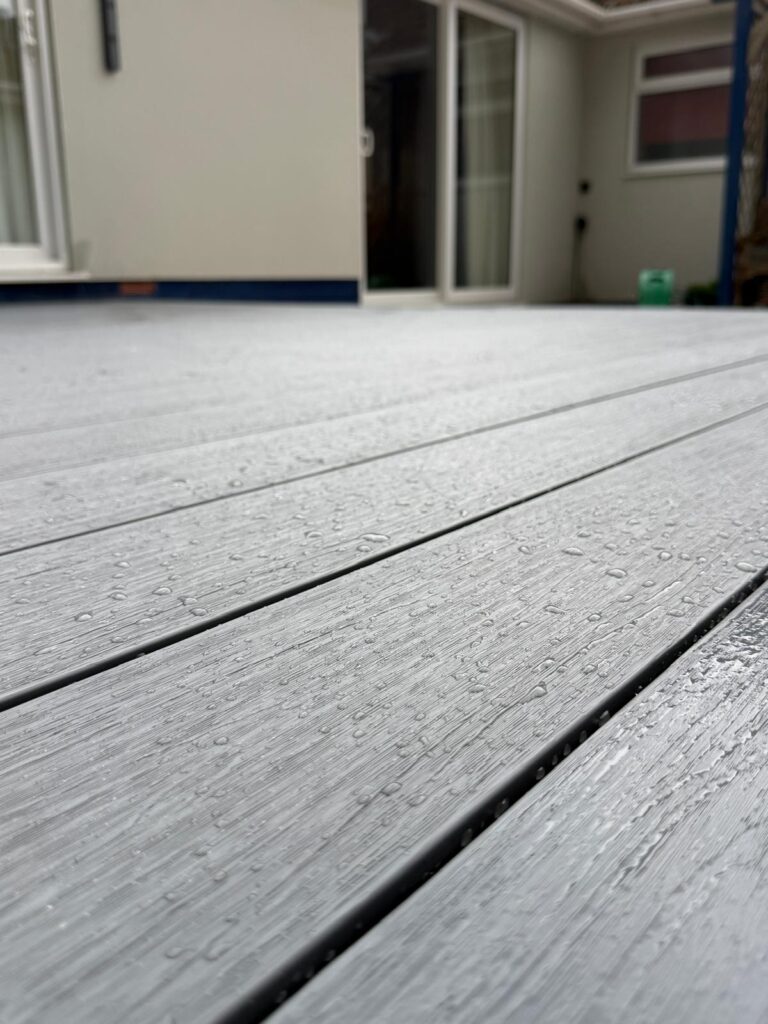 Close-up of rain beading on woodgrain composite decking boards, showing the texture of a low maintenance decking surface