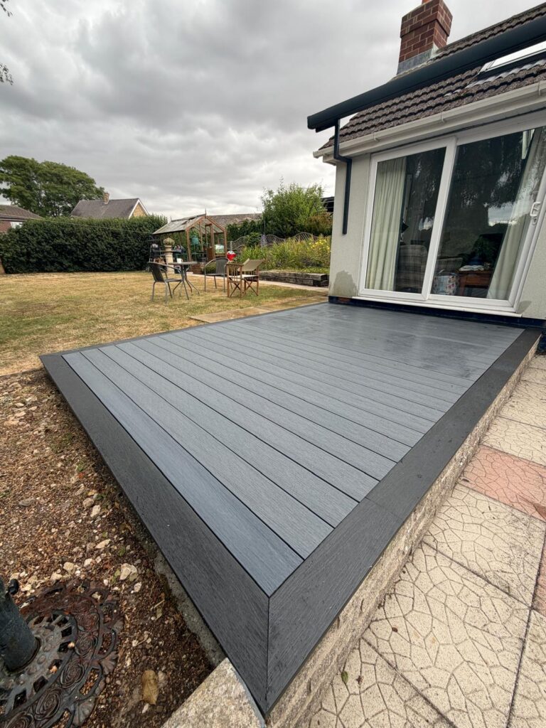 New composite decking with dark edging boards outside a white rendered bungalow, fitted by decking installers in Lincolnshire