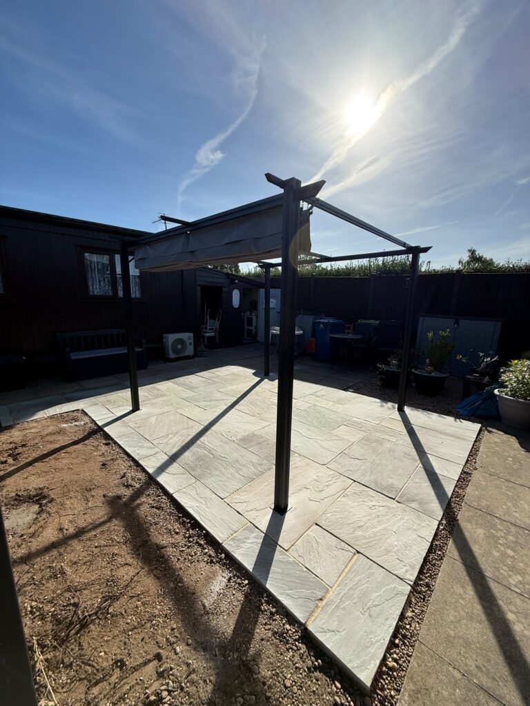Pergola with a retractable canopy on a new sandstone patio edged with gravel, fitted by patio installers in Lincolnshire