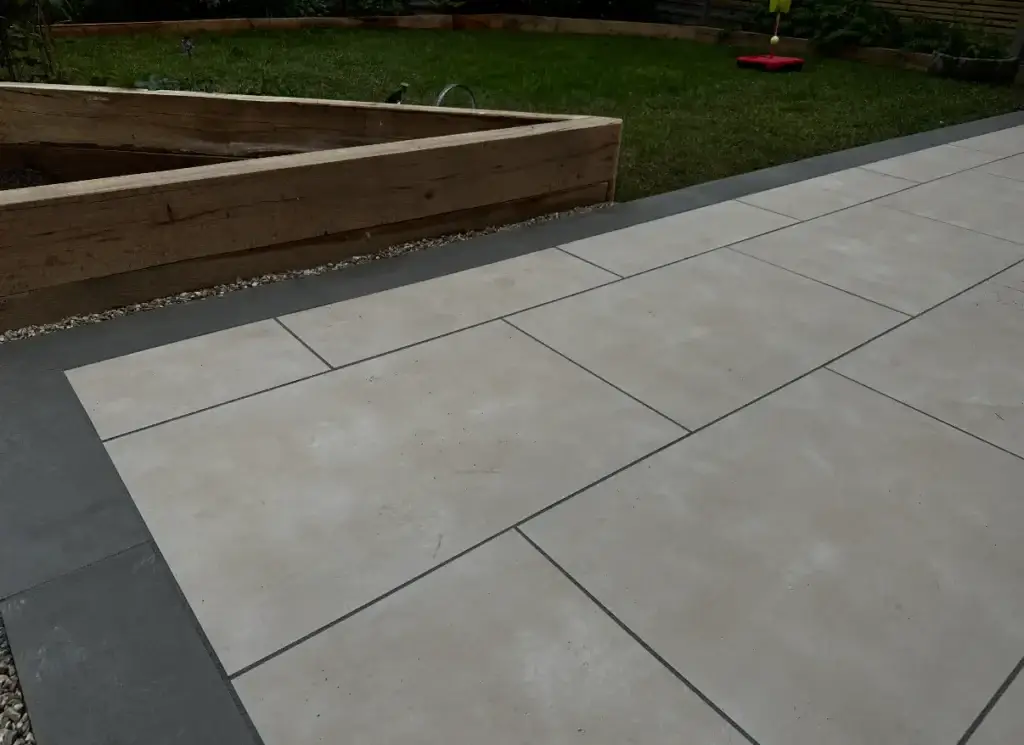 Close-up of light cream porcelain patio installation with dark border detailing in Lincoln by garden landscapers in Lincoln