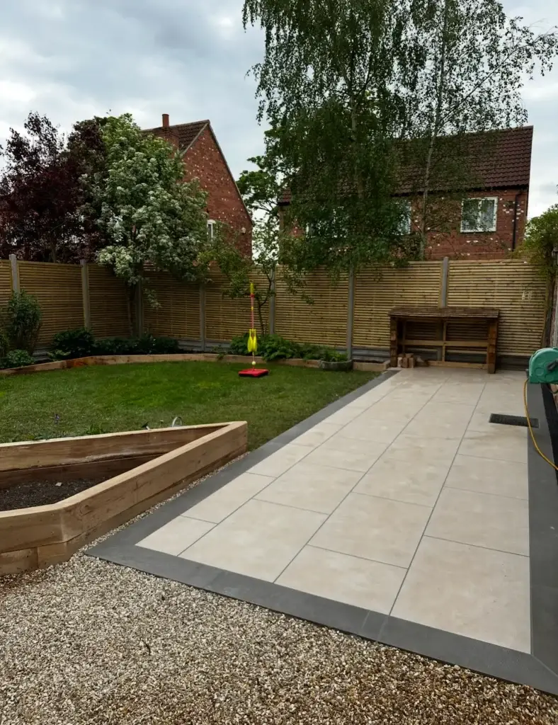 Modern porcelain patio installation with dark edging and raised sleeper beds in Lincoln.
