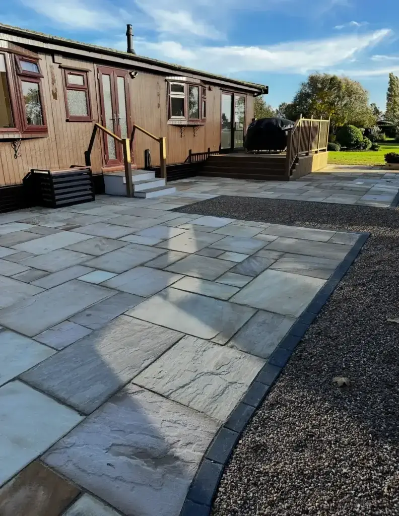 New light sandstone patio with contrasting edging and raised composite decking completed by garden landscapers in Lincoln