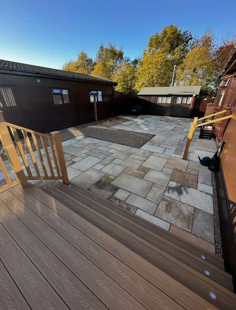 Composite decking installation overlooking a light sandstone patio with gravel borders, completed by landscapers in Lincoln