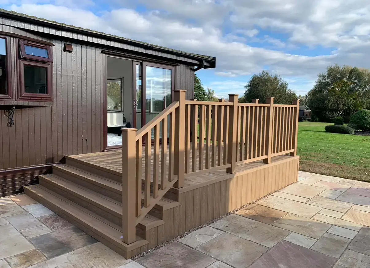 Raised composite decking with handrail above a cream sandstone patio, installed by Reshape Landscaping Ltd in Gainsborough