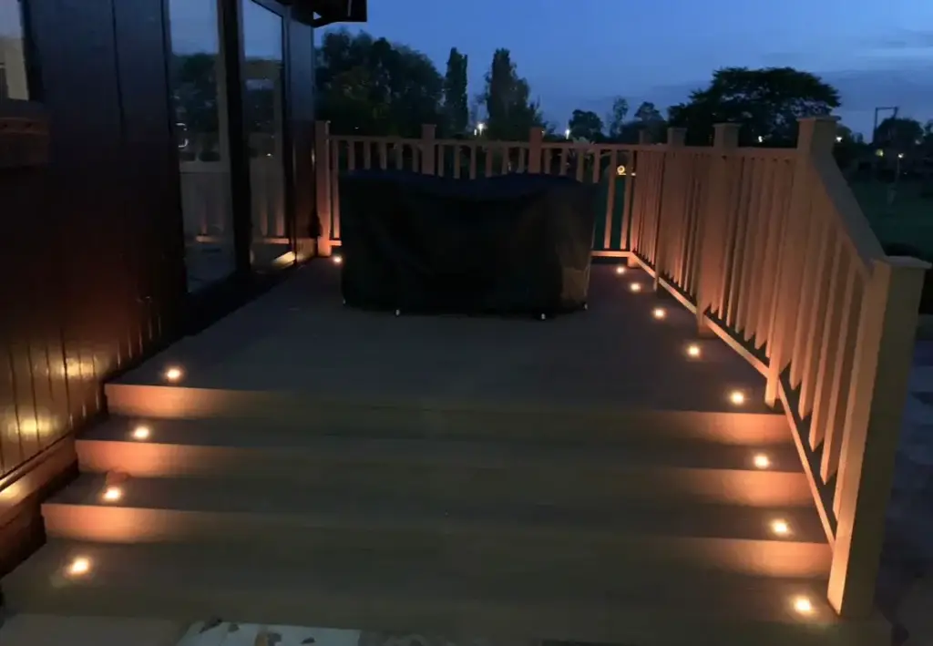 Evening view of composite decking with soft amber LED step lighting, installed by landscape gardeners in Torksey near Gainsborough