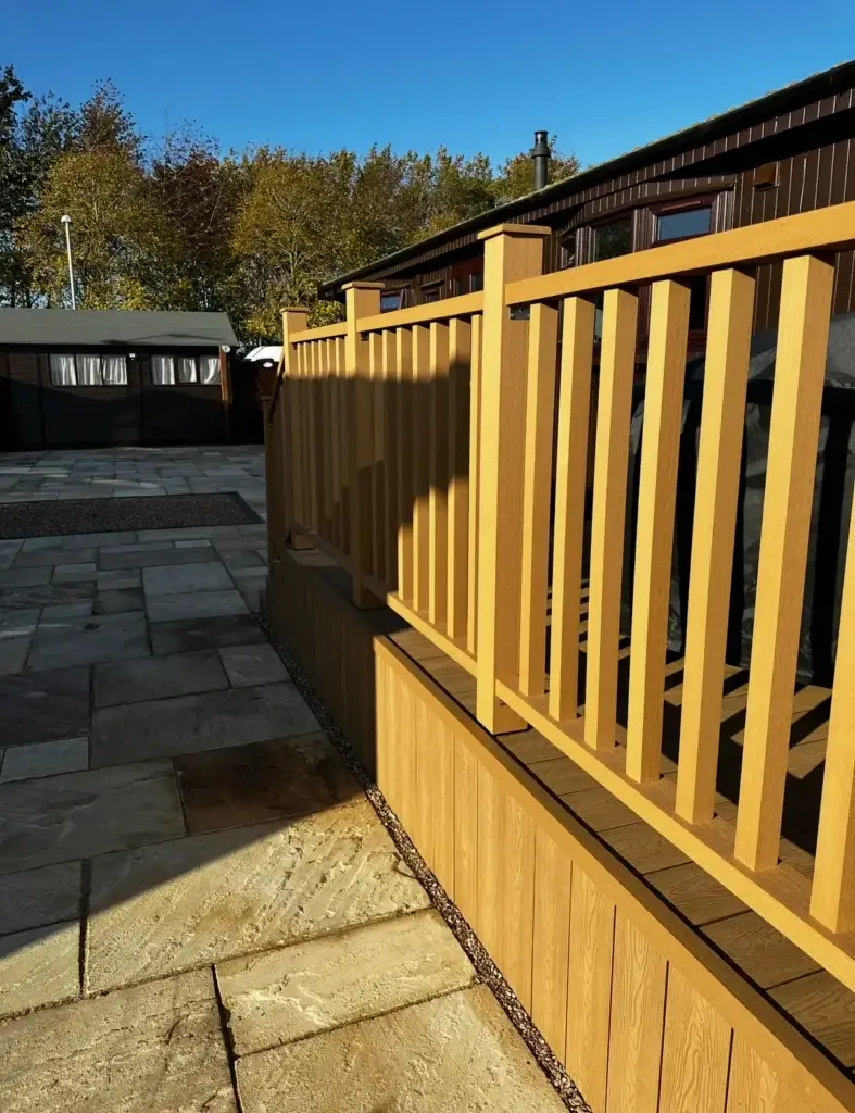 Light oak composite decking installation with vertical balustrade and matching cladding installed by landscapers in Lincoln.