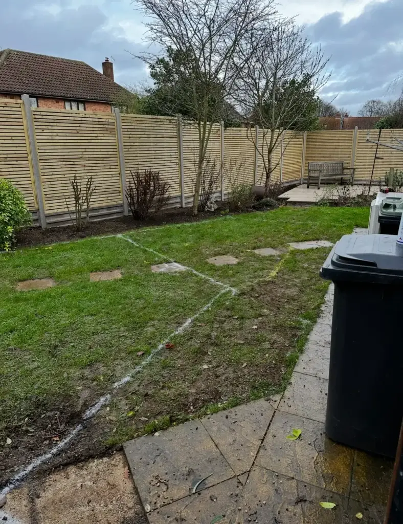 Garden landscapers in Lincoln marking out garden layout beside slatted fencing installation.