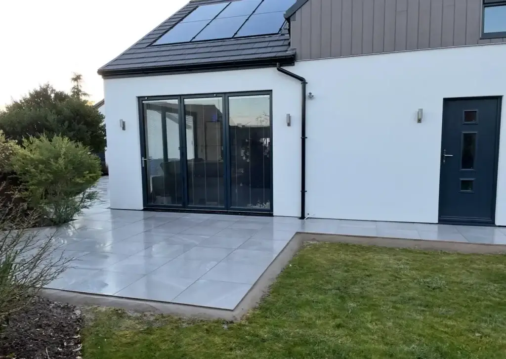 Modern grey porcelain patio installation in Gainsborough with clean lawn border