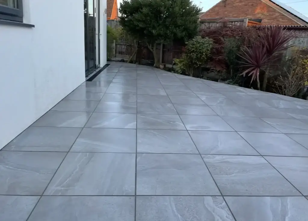 Grey porcelain patio installation in Lincoln with large format tiles and modern garden border