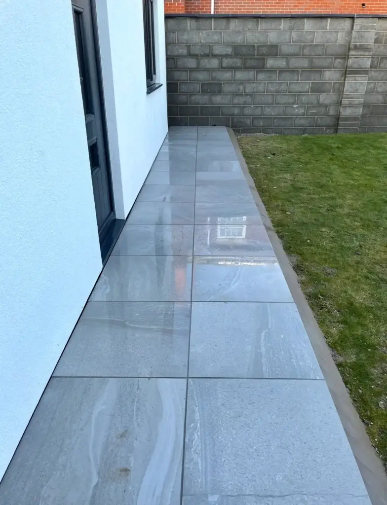 Grey porcelain garden walkway installation in Lincoln with stone effect tiles and lawn edging