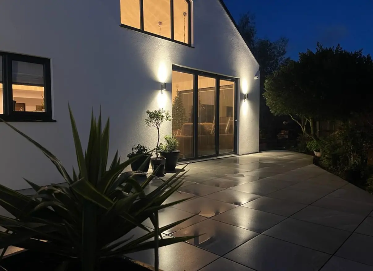 House garden with outside lights shining on porcelain patio