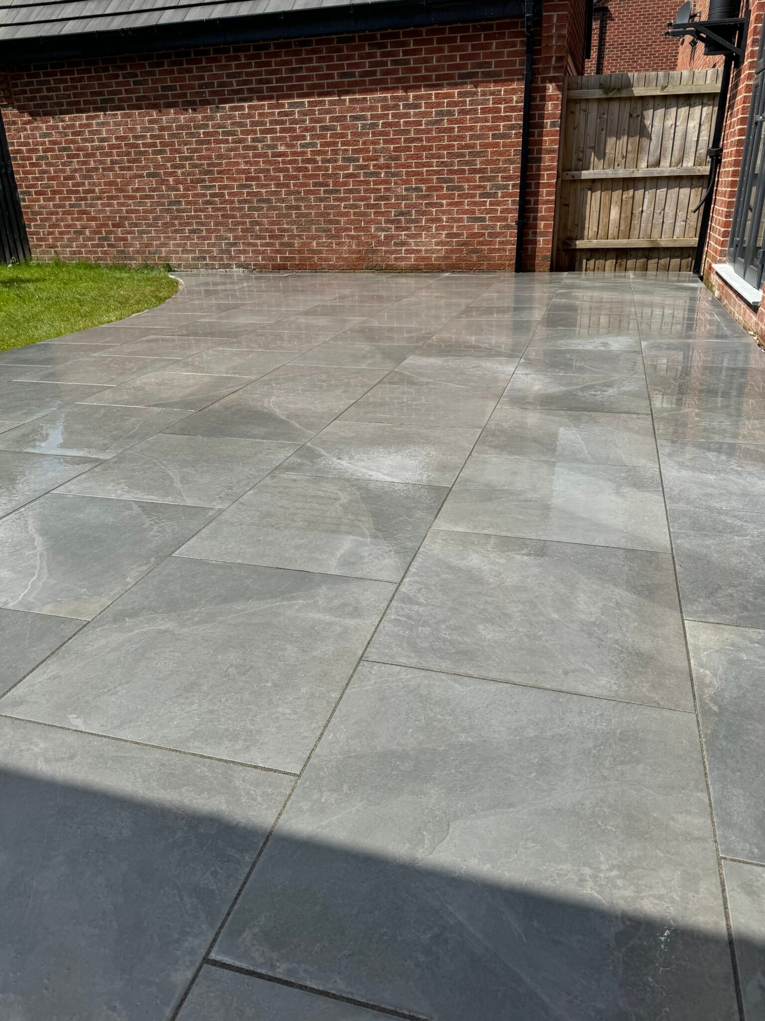 Grey porcelain patio installation in Lincolnshire by Reshape Landscaping Ltd, featuring smooth large-format tiles and a sleek contemporary finish