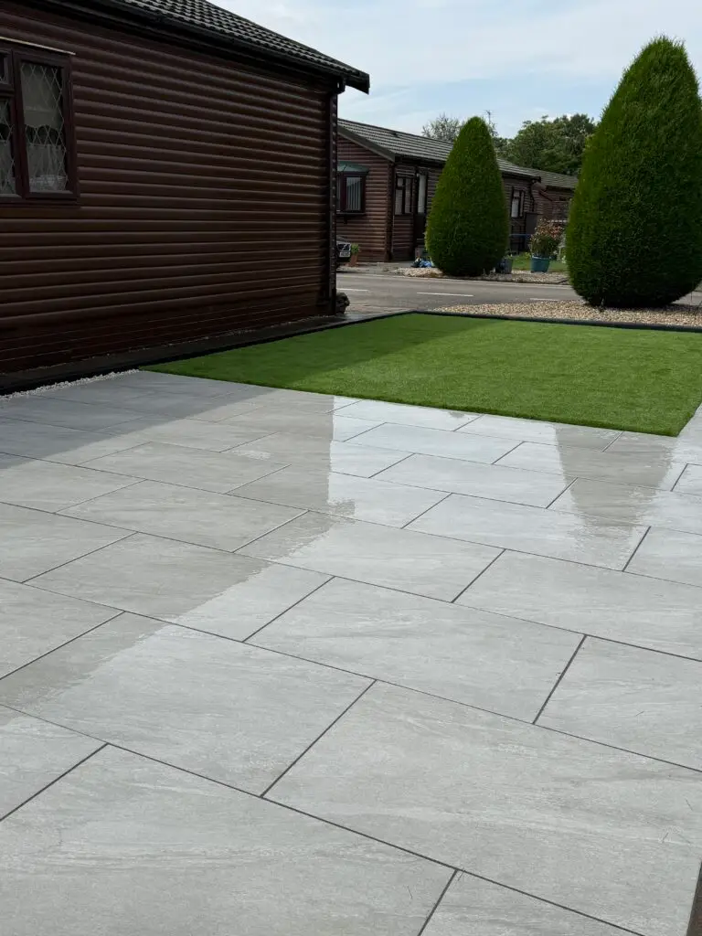 Light grey porcelain patio installation in Gainsborough The Elms by landscape gardeners featuring smooth large-format slabs and low-maintenance artificial lawn