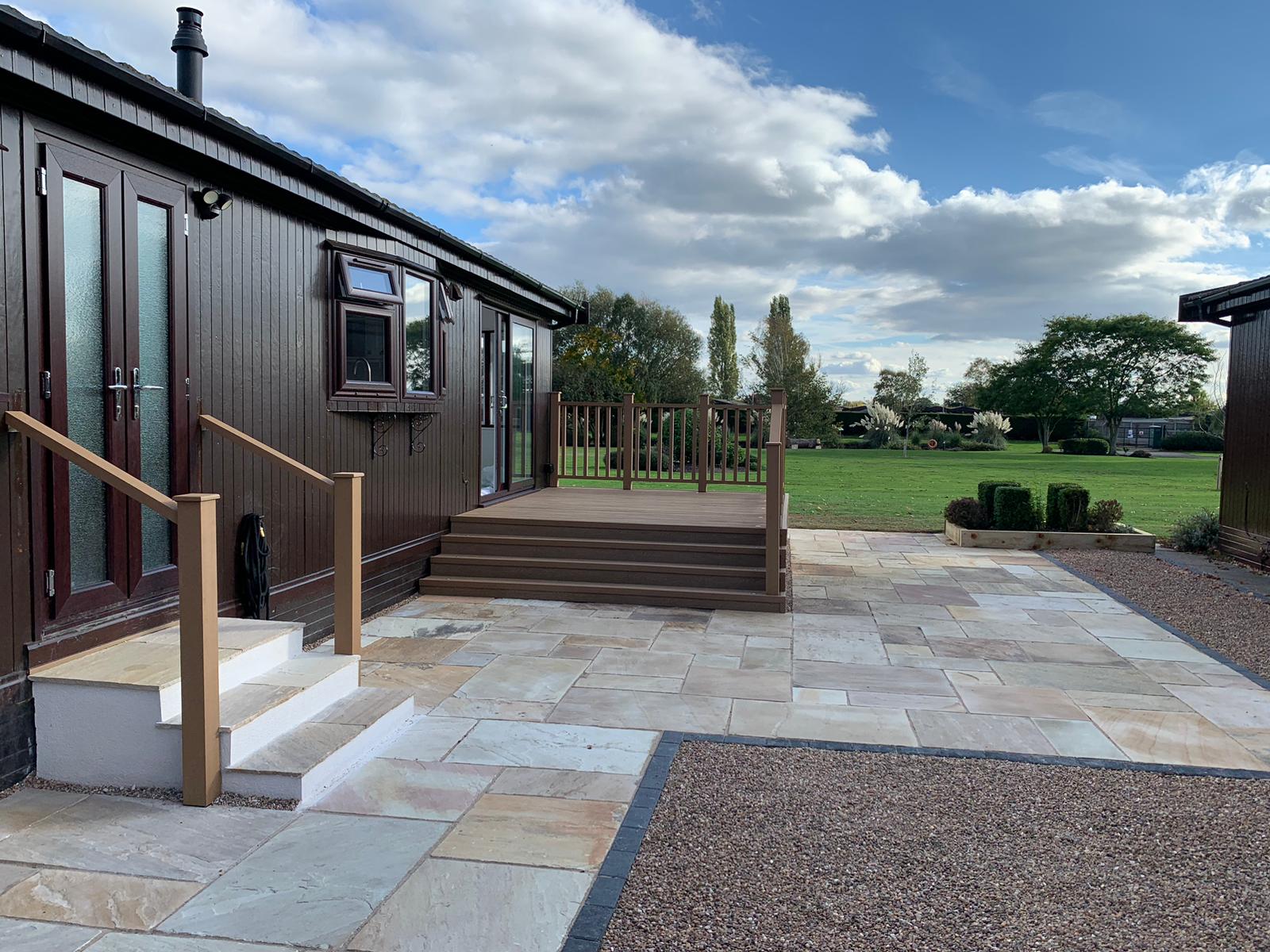 Natural sandstone patio and wooden decking installation in Lincoln featuring warm tones and modern garden design