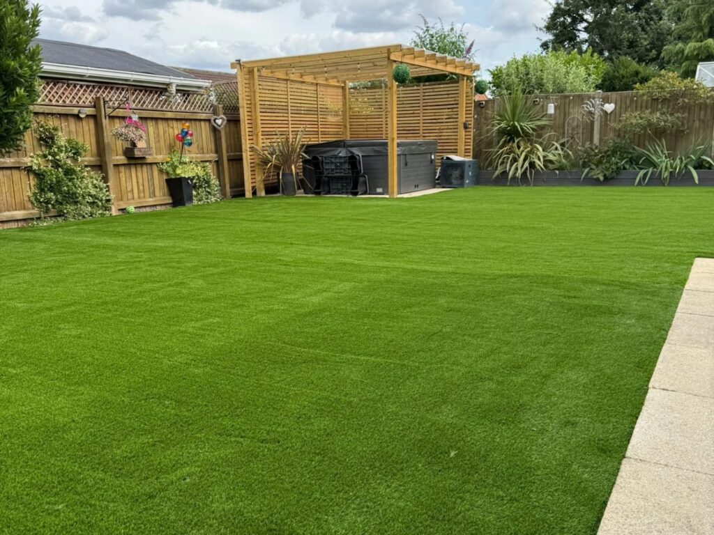 Wide artificial grass lawn with a timber pergola and hot tub, laid by artificial grass Lincoln installers