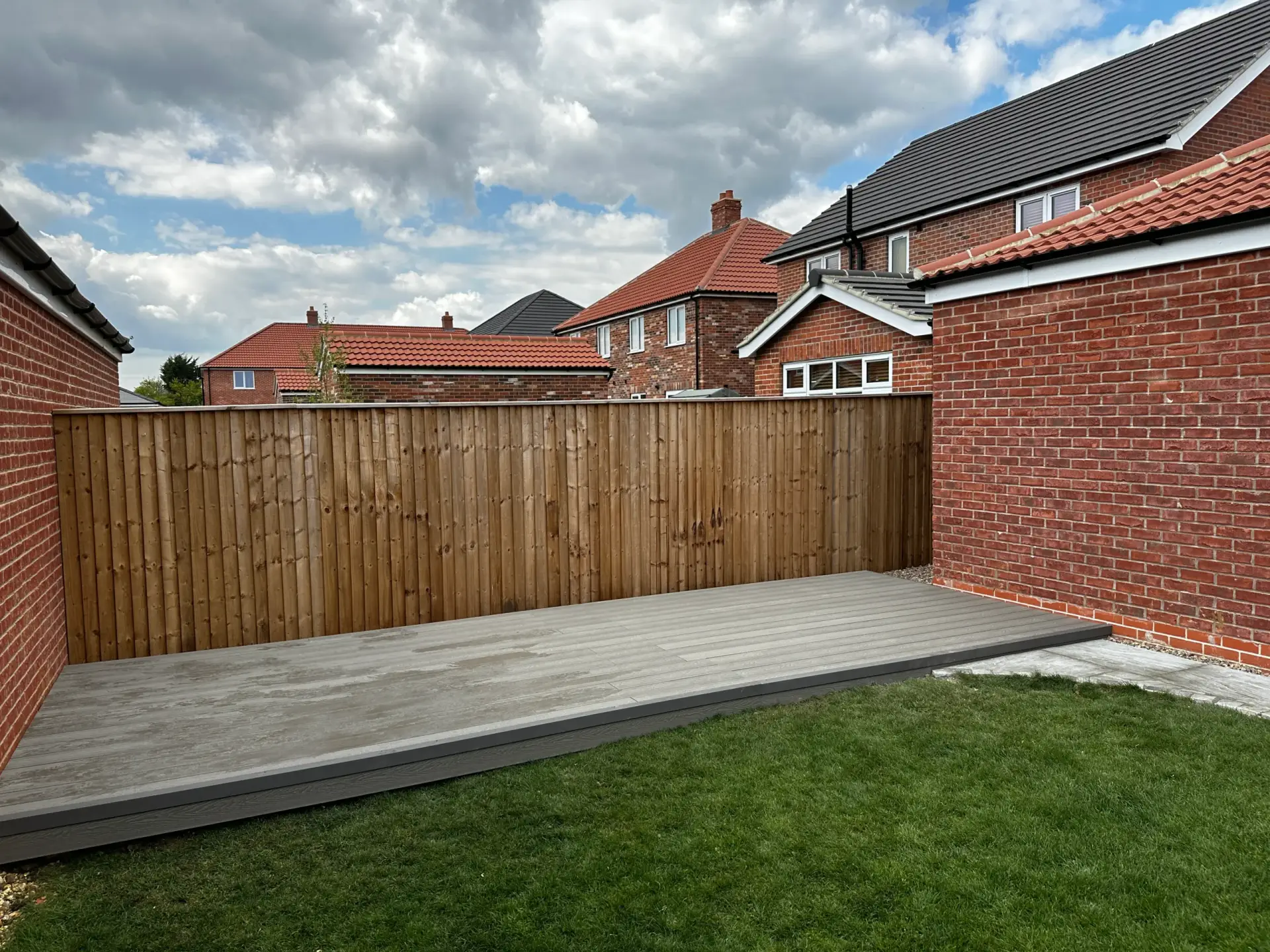 New turf lawn beside grey composite decking and a timber fence in a new-build garden, by Lincolnshire landscapers